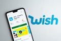 Wish shopping app in Play Market on the smartphone, placed on the brochure with Wish logo