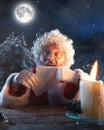 Emotional Santa Claus congratulating with New Year and Christmas, sending a letter, wish list in midnight with candle Royalty Free Stock Photo