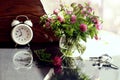 Wishes for a good summer day: a bouquet of wild flowers in a glass vase, a white alarm clock with reflection, a bunch of old keys Royalty Free Stock Photo