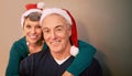 Wishing you a merry Christmas. Portrait of a happy mature couple wearing santa hats at Christmastime. Royalty Free Stock Photo