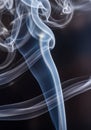 Wispy trails of smoke against a dark background create an abstract pattern. The Royalty Free Stock Photo