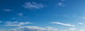 Wispy white clouds drifting across blue sky, panorama format. Royalty Free Stock Photo