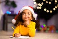 Wistful little afro girl thinking about letter to Santa Claus