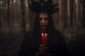 witch in a black costume holds candles in a dark forest Royalty Free Stock Photo