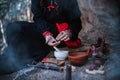 A witch in a black long dress of Slavic style is holding a magic rite in the mountains. A woman conjured in a dark forest