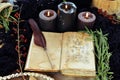 Witch book of spells with black candles on altar table.