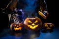 Witch casts a spell on a steaming pumpkin in the dark on Halloween