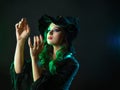 A witch creates magic, a young beautiful brunette in a pointed hat. Royalty Free Stock Photo