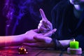 Witch is a fortune teller reading good luck close-up. Fortune teller guides the lines on the client's hand in neon light Royalty Free Stock Photo