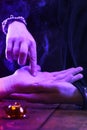 Witch is a fortune teller reading good luck close-up. Fortune teller guides the lines on the client& x27;s hand in neon light Royalty Free Stock Photo