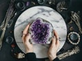 The witch is holding amethyst stone surrounded magic things