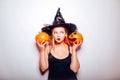 The witch listens to the pumpkins, the model is shocked. Woman with hat and black dress, halloween party Royalty Free Stock Photo