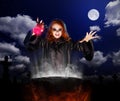 Witch with red potion and cauldron on night sky background Royalty Free Stock Photo