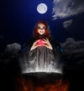Witch with red potion and cauldron on night sky background Royalty Free Stock Photo