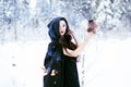 Witch or woman in black cloak with fire ball in white snow forest Royalty Free Stock Photo