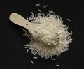Wite basmati rice with wooden scoop on black background. Flat lay.