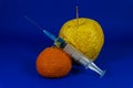 Withered orange and apple with hypodermic needle