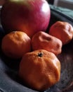 Withered oranges and an apple on a tarnished silver dish