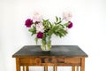 Withered pink and crimson peonies stand in transparent glass vase on old wooden vintage table. White background Royalty Free Stock Photo