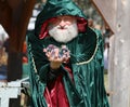 Wizard in a green cloak with a hood with magic balls in his hands, a costume performance at a medieval fair, community event