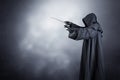 Wizard with hooded cape and magic wand over dark background Royalty Free Stock Photo