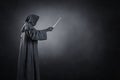 Wizard with hooded cape and magic wand over dark background Royalty Free Stock Photo