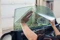 The wizard for installing additional equipment sticks a tint film on the side front glass of the car and flattens it by hand to Royalty Free Stock Photo
