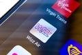 Wizz Air app on the screen and a finger about to choose it. It is surrounded by Ryinair, Virgin Trains apps. Close up photo with s