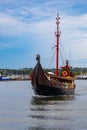 Beautiful wooden viking boat Rakkar with decorations around full of tourists at Baltic sea at