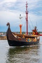 Beautiful wooden viking boat Rakkar with decorations around full of tourists at Baltic sea at