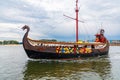 Beautiful wooden viking boat Rakkar with decorations around full of tourists at Baltic sea at