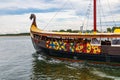 Beautiful wooden viking boat Rakkar with decorations around full of tourists at Baltic sea at