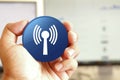 Wlan network icon blue round button holding by hand infront of workspace background