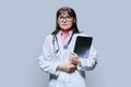 Wman doctor holding laptop looking at camera on grey background Royalty Free Stock Photo