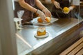 Wmployee puts bun with cream onto tray while colleague holds grater and lemon in bakery Royalty Free Stock Photo