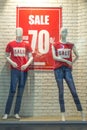 Wo female mannequins in red T-shirts and blue jeans in a shop window against a white brick wall background Royalty Free Stock Photo