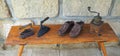 wo old rusty antique iron with wooden handle, hand coffee grinder and leather clogs on old wooden bench with sandstone wall Royalty Free Stock Photo