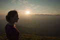 Woamn stands on a peak of mountain at sunset