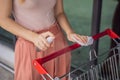 Woan hand disinfecting shopping cart with alcohol spray for corona virus or Covid-19 protection