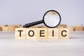 woden blocks with a magnifying glass text: TOEIC. Test Of English For International Communication