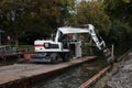 White Cat industrial digger floating on a raft barge on a river canal and excavating the bank Royalty Free Stock Photo