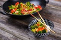 wok with vegetables, bowl of rice and chopsticks on wooden ground Royalty Free Stock Photo