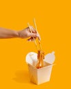 Wok noodles in paper box fast food yellow background Royalty Free Stock Photo