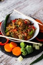 Wok, noodles, udon with pork and pineapple, on black plate and a wooden white background Royalty Free Stock Photo