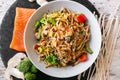 Wok, noodles, udon with salmon, on black plate and a wooden white background top view