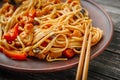 Wok udon stir fry noodles with chicken and vegetables in plate and chopsticks on black wooden background Royalty Free Stock Photo