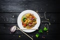 Wok. Udon stir fry noodles with chicken and vegetables in a white plate on black wooden background. With chopsticks and Royalty Free Stock Photo