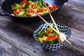 Wok with vegetables, bowl of rice and chopsticks on wooden groun Royalty Free Stock Photo