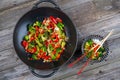 Wok with vegetables, bowl of rice and chopsticks on wooden groun Royalty Free Stock Photo
