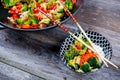 wok with vegetables, bowl of rice and chopsticks on wooden groun